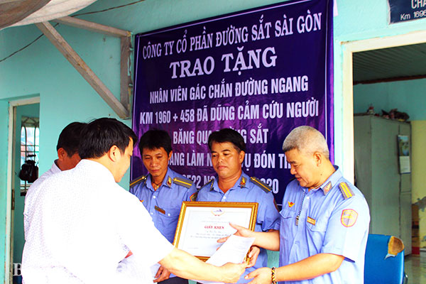 Đại diện Công ty cổ phần đường sắt Sài Gòn tặng giấy khen cho ông Trần Văn Năm (giữa) và tổ trực gác chắn. Ảnh: T.Hải