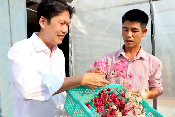 Ông Hoàng Sơn Công (trái) trao đổi với nông dân xã Mã Đà (H.Vĩnh Cửu) về giải pháp sấy hoa giấy bằng lò sấy năng lượng mặt trời
