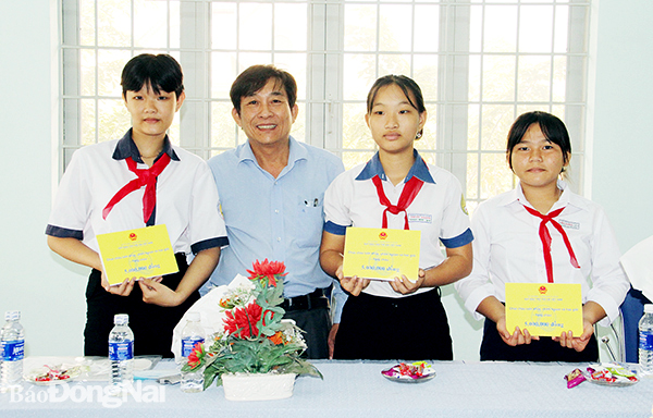 Ông Hoàng Văn Long, Giám đốc Quỹ Bảo trợ trẻ em tỉnh trao học bổng dài hạn cho các em học sinh. Ảnh: Văn Truyên