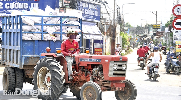 Xe máy cày chở thức ăn chăn nuôi di chuyển trên quốc lộ 1 đoạn qua xã Tây Hòa (H.Trảng Bom)