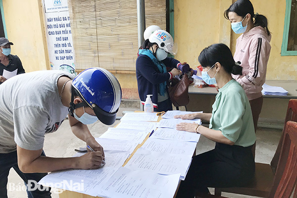 Phụ huynh học sinh đến nộp và nhận phiếu bài tập về nhà tại Trường tiểu học Chu Văn An (H.Xuân Lộc) (ảnh trên)