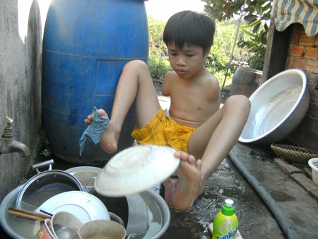 Cậu bé “chim cánh cụt” Hồ Hữu Hạnh dù bị khuyết đôi tay nhưng em vẫn có thể làm mọi việc bằng đôi chân của mình (Ảnh do nhân vật cung cấp)