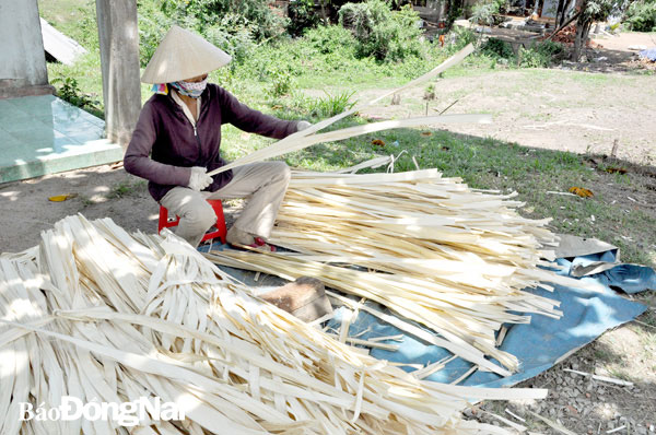 Bà Lê Thị Xuân (44 tuổi, ngụ xã Xuân Hưng, H.Xuân Lộc) thực hiện công đoạn chuốt lá buông. Ảnh: Hoàng Dương