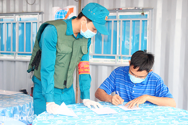 Lực lượng dân quân tự vệ hướng dẫn người dân khai báo y tế tại chốt kiểm soát trên đường tỉnh 768 (H.Vĩnh Cửu). Ảnh: Hạnh Dung