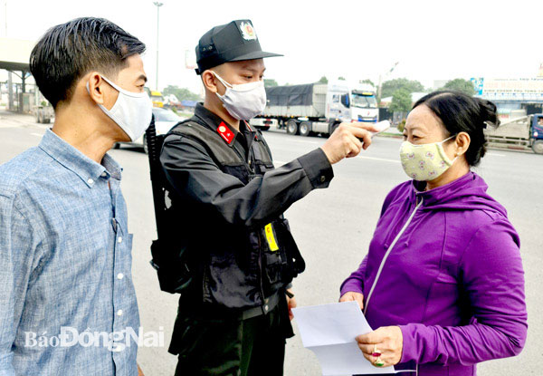 Công an tỉnh sẽ tăng cường cảnh sát cơ động tham gia tại các chốt kiểm soát dịch. Trong ảnh: Một chiến sĩ cơ động đo thân nhiệt cho người dân tại Chốt kiểm soát dịch số 1 trên tuyến quốc lộ 1, đoạn cầu Đồng Nai.