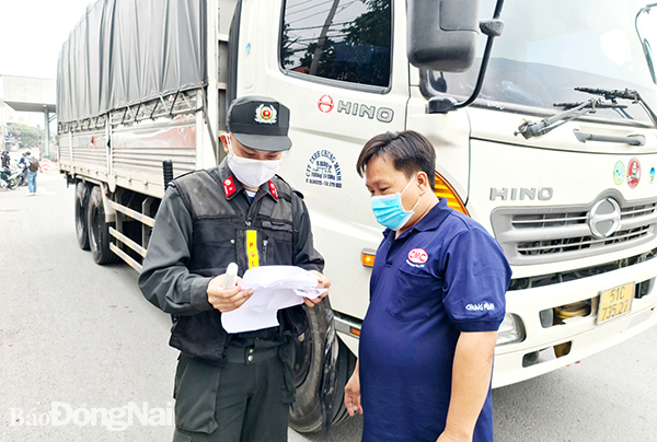 Lực lượng chức năng kiểm tra y tế đối với một trường hợp xe vận chuyển hàng hóa  tại Chốt kiểm soát dịch trên quốc lộ 1, đoạn qua cầu Đồng Nai (TP.Biên Hòa). Ảnh: T.Hải
