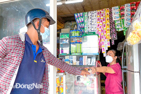 Bà Nguyễn Thị Bích Hoa, chủ tiệm tạp hóa trên đường Vũ Hồng Phô, P.An Bình (TP.Biên Hòa) giữ khoảng cách, tuân thủ thông điệp 5K khi bán hàng thiết yếu cho khách. Ảnh: Đăng Tùng