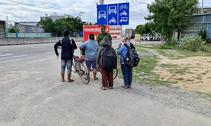 An officer wishes the family of four a safe journey after passing the Chung My Covid-19 checkpoint in Ninh Phuoc District, Ninh Thuan Province. Photo courtesy of Youth Police of Ninh Phuoc District.