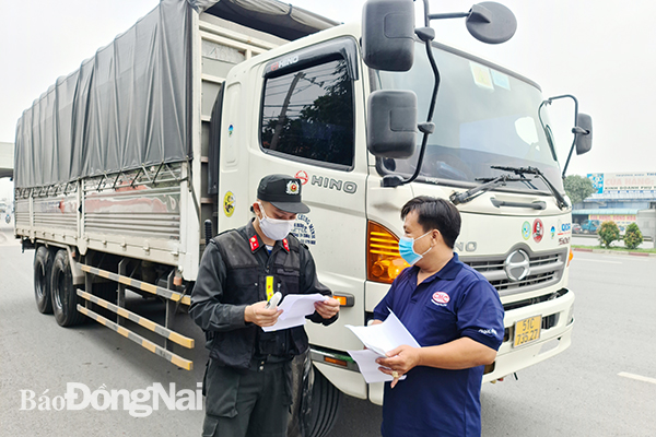Lực lượng chức năng kiểm tra y tế đối với lái xe vận chuyển hàng hóa tại chốt kiểm soát cầu Đồng Nai. (Ảnh minh họa: Thanh Hải)