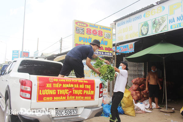 Các thành viên Đội xung kích phòng chống tội phạm và hỗ trợ giao thông TP.Biên Hòa xếp rau củ quả lên xe để chở đến các điểm tập kết và trao cho người dân. Ảnh: Tố Tâm