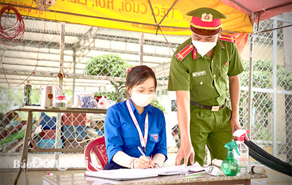 Phó bí thư Đoàn Thanh niên xã Ngọc Định, H.Định Quán Đặng Thị Bích Ngọc và trung úy Trương Văn Thanh, Công an xã đang thực hiện nhiệm vụ trực chốt kiểm soát dịch trên địa bàn. Ảnh: Thảo Lâm