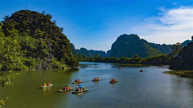 Tourists travel on boat along Ngo Dong river to enjoy the magnificent caves. 