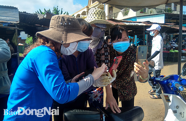 Các tiểu thương tại Chợ Long Khánh hào hứng khi được đoàn viên thanh niên hướng dẫn cài đặt ứng dụng PC-Covid