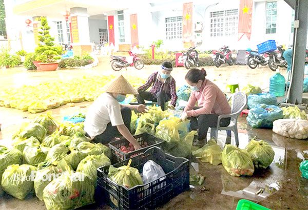 Chị Trần Thị Ngọc Trúc, Bí thư Chi bộ kiêm Trưởng ban Công tác Mặt trận ấp Chợ, xã Phước Thiền (bìa phải) đang phân chia thực phẩm để phát cho người dân gặp khó khăn trong dịch bệnh. Ảnh: Thảo Lâm