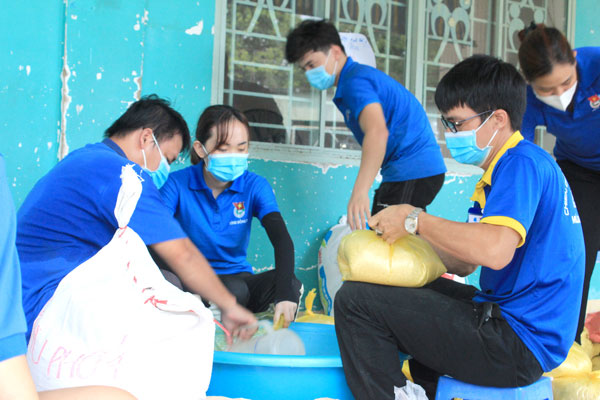 Tình nguyện viên là giáo viên ở H.Định Quán chi viện cho TP.Biên Hòa đang chuẩn bị những phần gạo hỗ trợ người dân. Ảnh: Nga Sơn