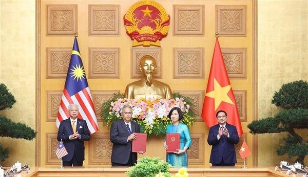 Malaysian Prime Minister Dato’ Sri Ismail Sabri bin Yaakob (L) and Prime Minister Pham Minh Chinh witness the signing of a cooperation agreement between the Vietnam News Agency (VNA) and Malaysian National News Agency (Bernama)