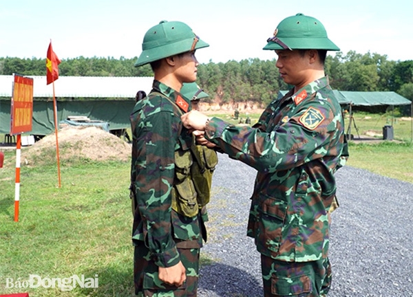 Thượng tá Bùi Anh Tuấn (Lữ đoàn trưởng Lữ đoàn 96, Binh chủng Pháo binh) cài hoa bắn giỏi cho chiến sĩ mới đạt thành tích cao. Ảnh: N.Hà