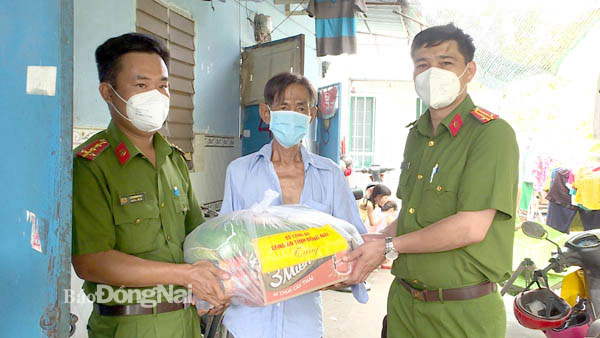 Cán bộ công an trao quà từ mô hình Gian hàng 0 đồng của Công an tỉnh cho người dân gặp khó khăn vì dịch bệnh tại TP.Biên Hòa. Ảnh: Trần Danh