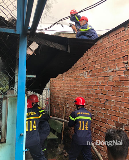 Lực lượng Cảnh sát phòng cháy, chữa cháy trèo lên mái xung quanh bên để tiếp cận dập tắt đám cháy căn nhà cấp 4 tại P.Quang Vinh (TP.Biên Hòa). Ảnh: CTV