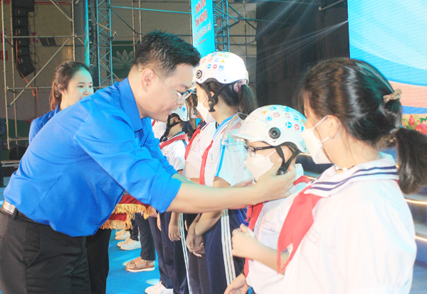 Anh Võ Văn Trung, Phó bí thư thường trực Tỉnh đoàn tặng mũ bảo hiểm cho các em thiếu nhi. Ảnh: N.Sơn