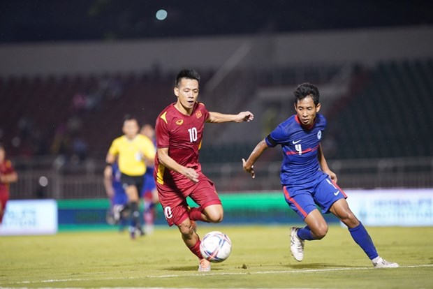 Nguyen Van Quyet of Vietnam (in red) and a Singaporean player vie for the ball at the game on September 21 evening. (Photo: VNA)