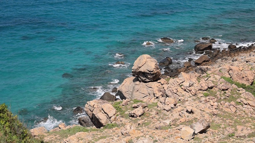 Deep blue water and shores of rocks in interesting natural shapes. 