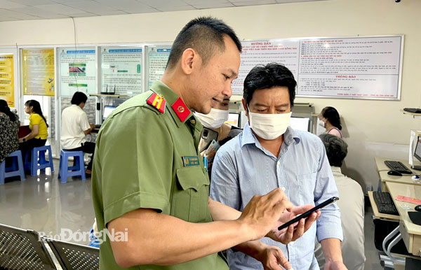 Cán bộ Phòng Quản lý xuất nhập cảnh Công an tỉnh hướng dẫn người dân đăng ký sử dụng tài khoản định danh điện tử trên phần mềm VNeID để hoàn tất thủ tục làm hộ chiếu online. Ảnh: K.Liễu