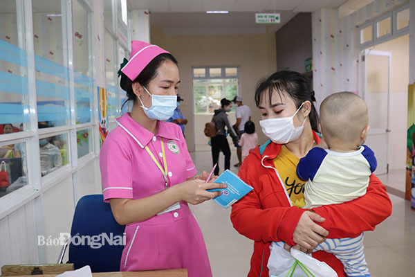 Nhân viên y tế hướng dẫn phụ huynh về vấn đề tiêm chủng cho trẻ tại Bệnh viện Nhi đồng Đồng Nai. Ảnh:  Hạnh Dung