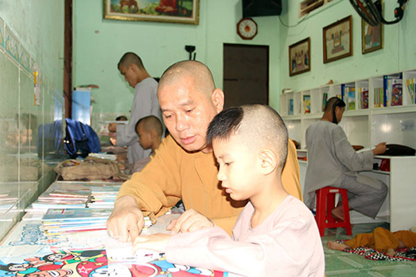 Thượng tọa Thích Nguyên Thông, Phó trưởng ban kiêm Chánh thư ký Ban Trị sự Giáo hội Phật giáo Việt Nam H.Long Thành, kèm trẻ tại thiền tự học bài. Ảnh: S.Thao