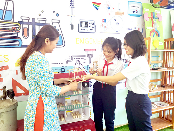 Nhóm học sinh Võ Ngọc Gia Hân, Phạm Mai Phương (Trường THCS Võ Trường Toản, H. Vĩnh Cửu) thảo luận cùng cô giáo tại phòng học STEAM. Ảnh: N.Hạ