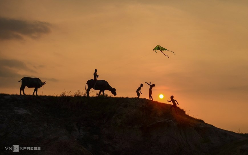 Buffalo herders fly a kite at dusk.