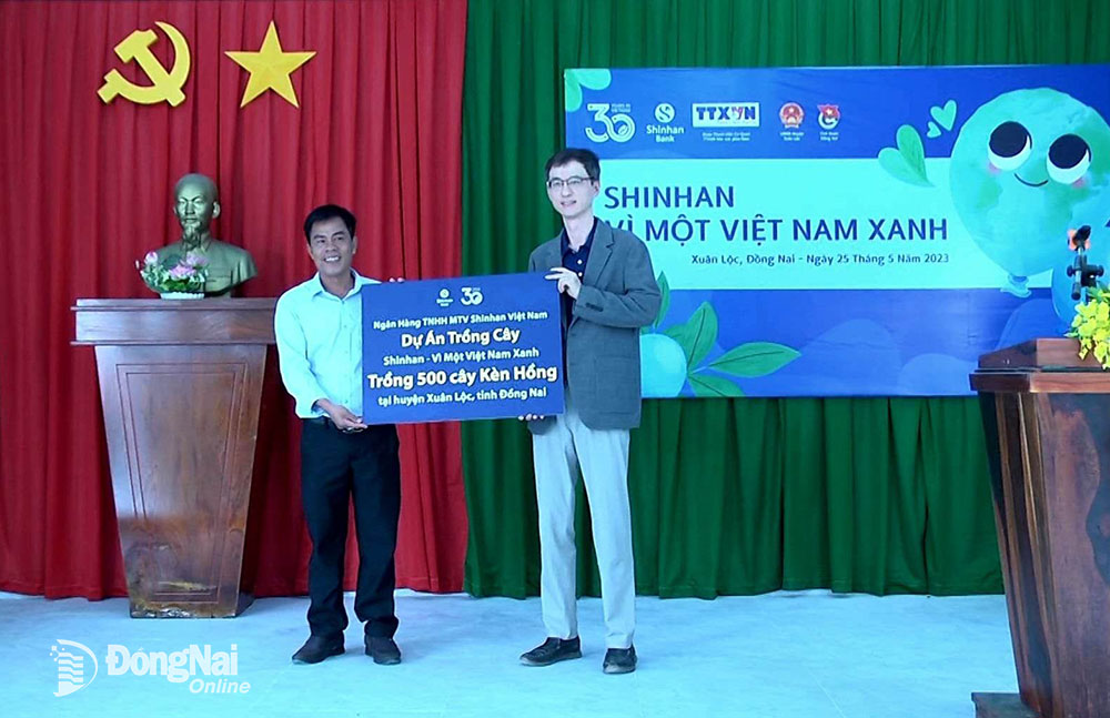 Đại diện Ngân hàng TNHH MTV Shinhan Việt Nam trao bảng tượng trưng Dự án “Trồng cây Shinhan - Vì một Việt Nam xanh” cho Bí thư Đảng ủy, Chủ tịch UBND xã Xuân Trường, H.Xuân Lộc