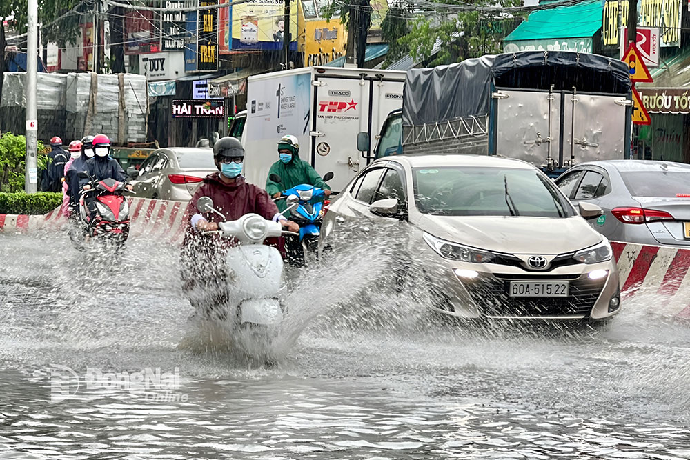 Các loại xe di chuyển qua điểm ngập tại khu vực ngã ba Trảng Dài (TP.Biên Hòa) trong cơn mưa chiều 26-5. Ảnh: Đăng Tùng
