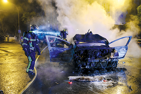 Lính cứu hỏa dập lửa một xe ô tô bị đốt cháy trong cuộc biểu tình bạo loạn ở Nantes, miền Tây Pháp, ngày 1-7-2023. Ảnh: AFP/TTXVN