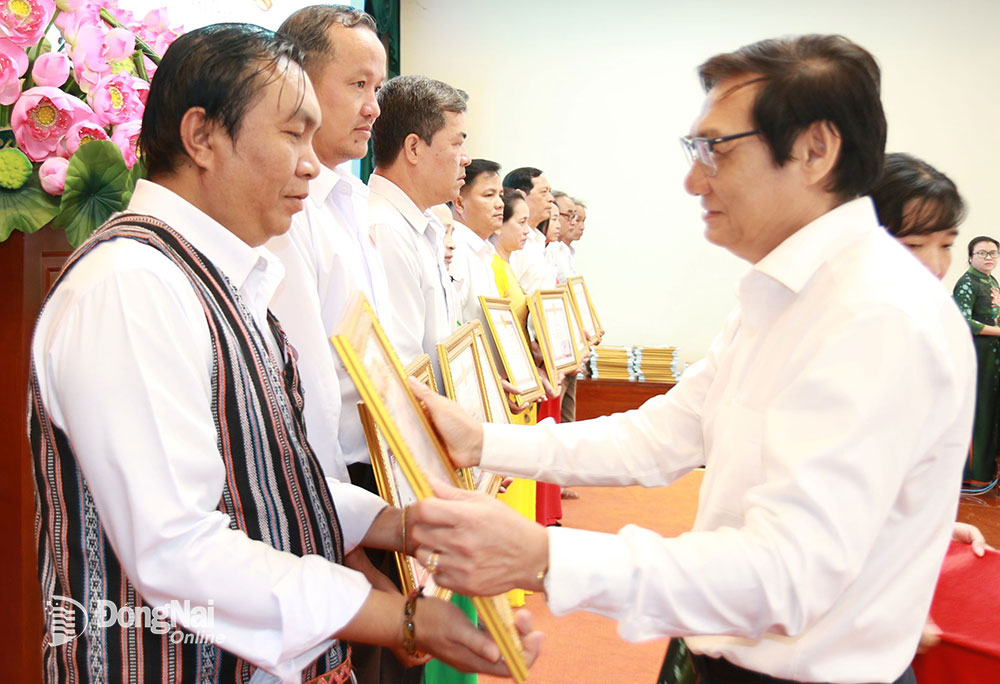 Phó chủ tịch UBND tỉnh Nguyễn Sơn Hùng tặng bằng khen của UBND tỉnh cho ông K’Luận tại Hội nghị tổng kết 20 năm tổ chức Ngày hội Đại đoàn kết toàn dân tộc ở khu dân cư trên địa bàn tỉnh Đồng Nai, giai đoạn 2003-2023. Ảnh: S.Thao